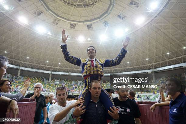 Spanish matador Emilio de Justo salutes his fans as he sits on the shoulders of a man at the end of a bullfight of Victorino Martin during the San...