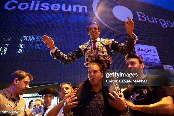 Spanish matador Emilio de Justo salutes his fans as he sits on the shoulders of a man at the end of a bullfight of Victorino Martin during the San...