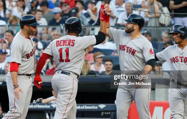 Rafael Devers of the Boston Red Sox celebrates his first inning grand slam home run against the New York Yankees with teammates J.D. Martinez , Mitch...