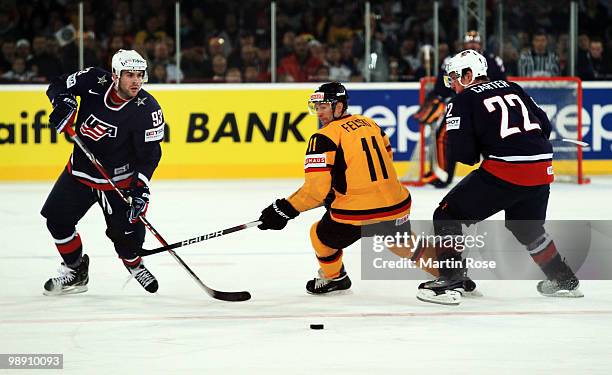 Sven Felski of Germany and Keith Yandle and Ryan Carter of USA battle for the puck during the IIHF World Championship group D match between USA and...