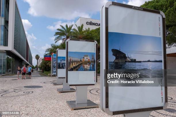 People stand near pictures from the open air photo exhibition "Voce Nao Esta Aqui" by Portuguese photojournalist Bruno Portela depicting the area as...