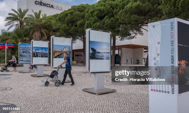 Visitors walk by pictures from the open air photo exhibition "Voce Nao Esta Aqui" by Portuguese photojournalist Bruno Portela depicting the area as...