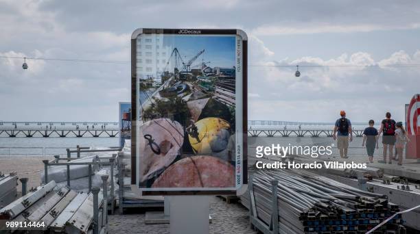 Visitors walk past pictures from the open air photo exhibition "Voce Nao Esta Aqui" by Portuguese photojournalist Bruno Portela, depicting the area...