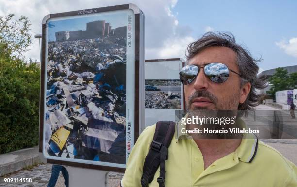 Portuguese photojournalist Bruno Portela stands before some of his photos during a guided tour of his open air photo exhibition "Voce Nao Esta Aqui"...