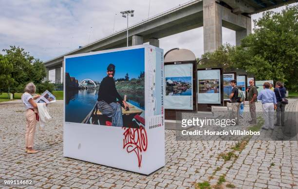 Visitors are briefed on pictures from the open air photo exhibition "Voce Nao Esta Aqui" by Portuguese photojournalist Bruno Portela, depicting the...