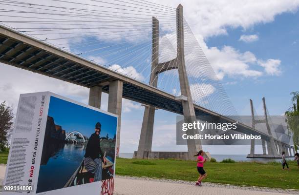 Woman jogs near Vasco da Gama bridge by the open air photo exhibition "Voce Nao Esta Aqui" by Portuguese photojournalist Bruno Portela, depicting the...