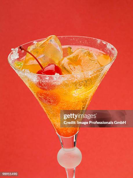 tequila sunrise with ice cubes and cocktail cherries, close-up - tequila sunrise stock pictures, royalty-free photos & images