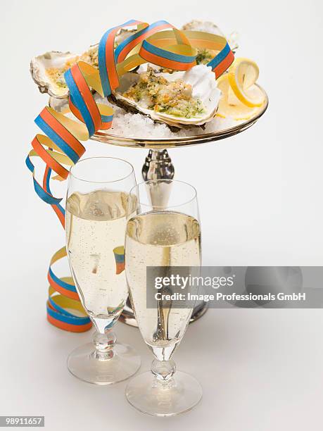 oysters gratin with paper streamer and glasses of sparkling wine, close up - muschel close up studioaufnahme stock-fotos und bilder