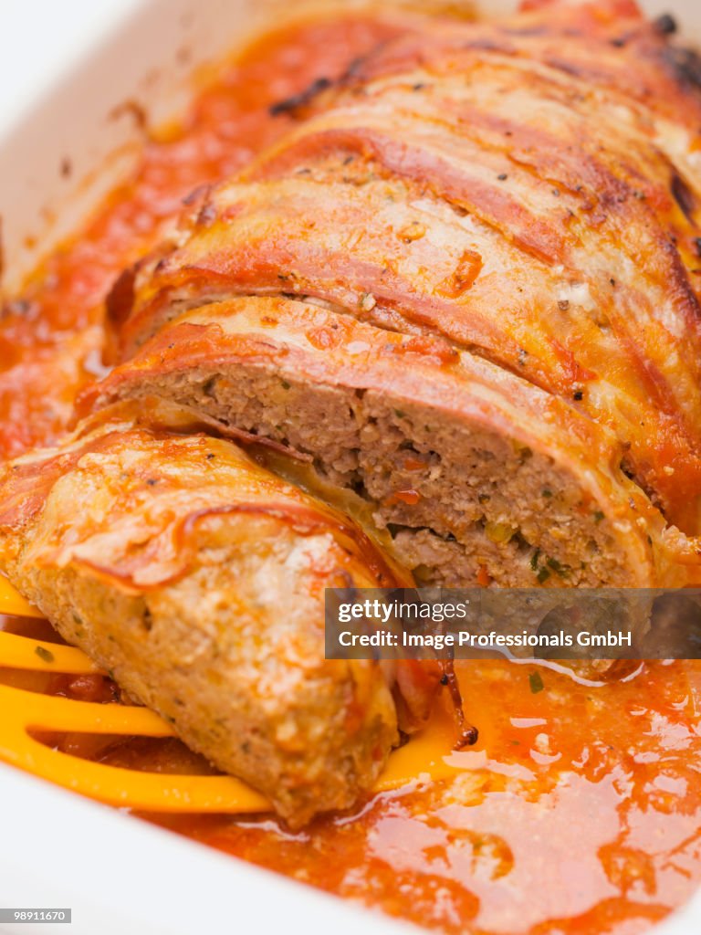 Bacon wrapped meatloaf in tomato sauce, close-up