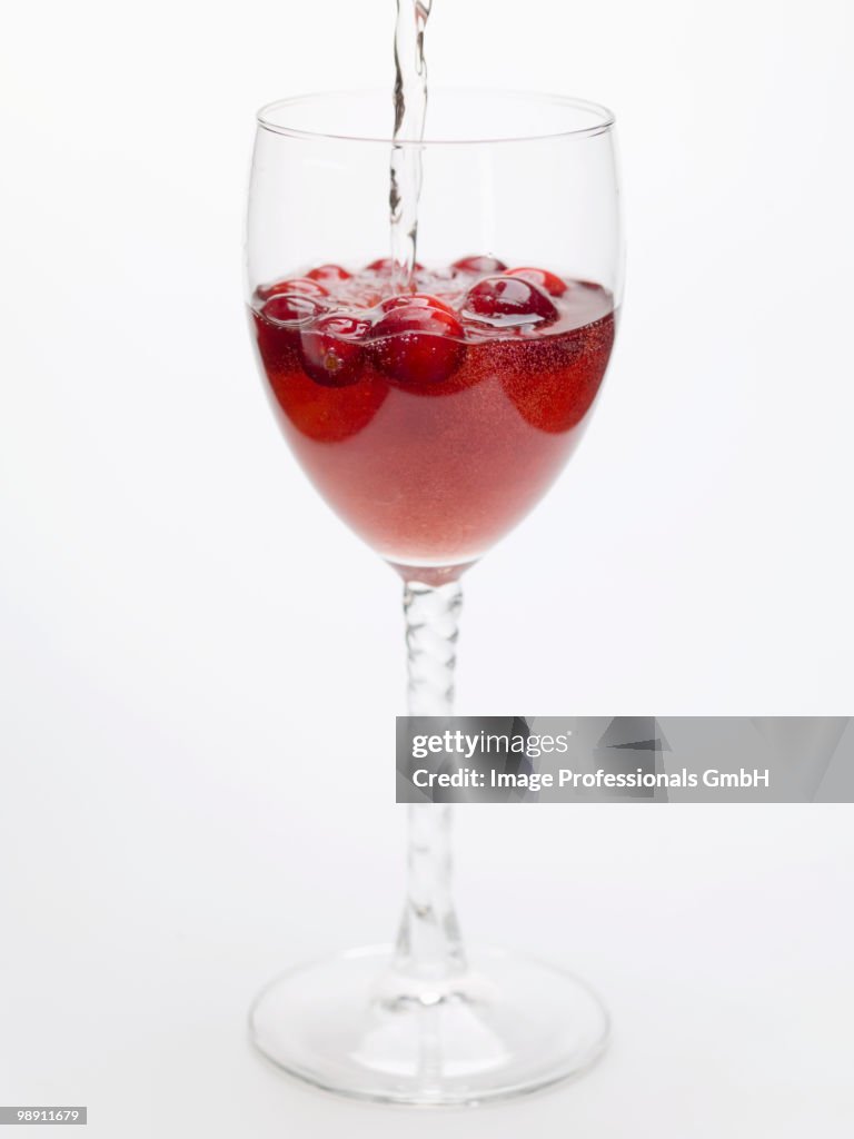 Pouring soda water to cranberry drink, close-up