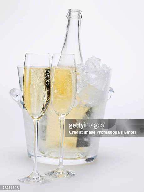two glasses of sparkling wine, wine bottle in ice bucket, close-up - champagner gläser mit flasche unscharfer hintergrund stock-fotos und bilder