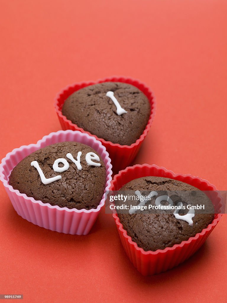 Heart shaped chocolate muffins on red background, close-up