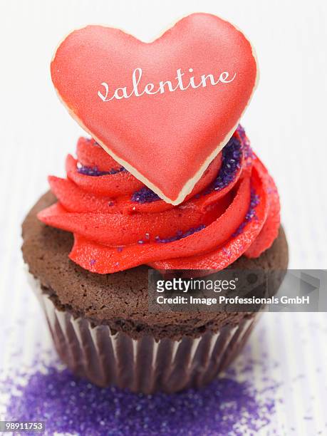 chocolate muffin with red cream and heart shaped biscuit, close-up - forma de queque imagens e fotografias de stock
