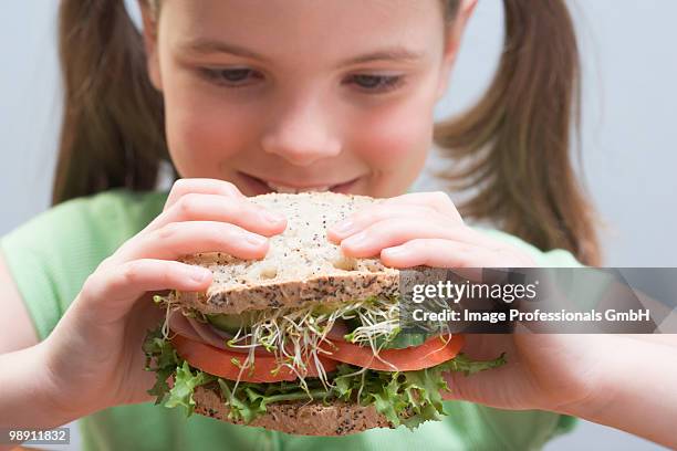 girl (6-7) holding large sandwich, close-up - large cucumber stockfoto's en -beelden