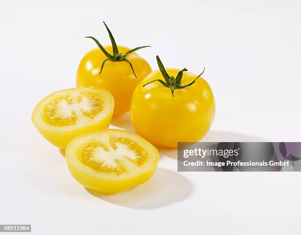 whole and halved yellow tomatoes on white background, close-up - イエロートマト ストックフォトと画像