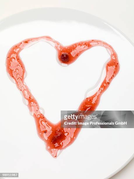 heart drawn in cranberry sauce on plate, overhead view, close-up - cranberry heart stock-fotos und bilder