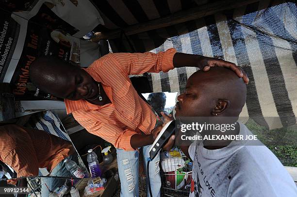 An road side hair dresser shaves a customer in the township of Alexandra in Johannesburg on May 7, 2010. All of the street names in the township have...