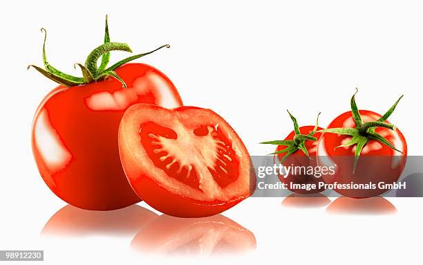 three whole and one halved tomato on white background with reflection, close-up - sepal stock pictures, royalty-free photos & images