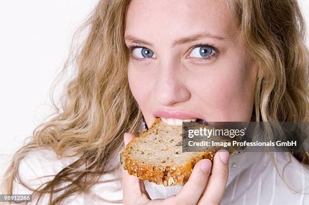 young woman eating slice of granary bread, close-up - eating brown bread stock pictures, royalty-free photos & images