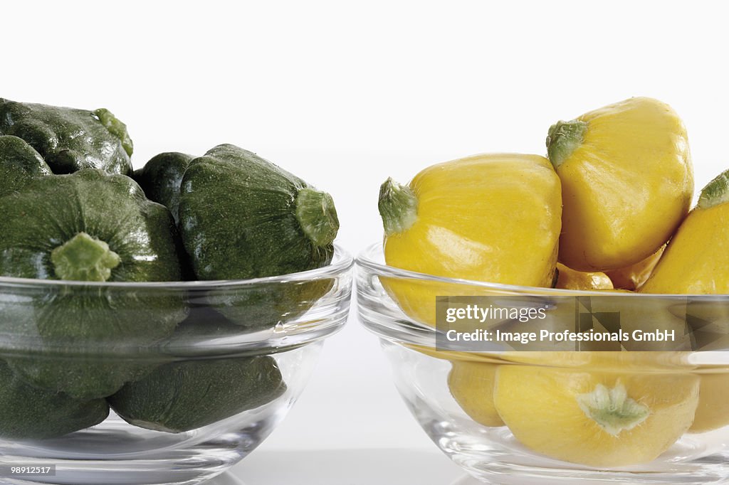 Green and yellow patty pan squashes in glass bowls, close-up