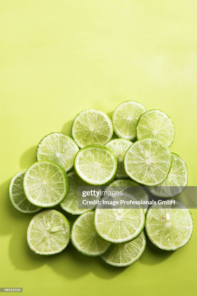 Key lime slices on green background, overhead view, close-up