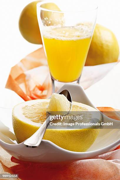 halved grapefruit with spoon and grapefruit juice, close-up - viereckiger teller stock-fotos und bilder