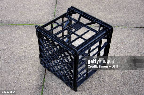 black plastic milk crate on a concrete sidewalk - crate stock pictures, royalty-free photos & images