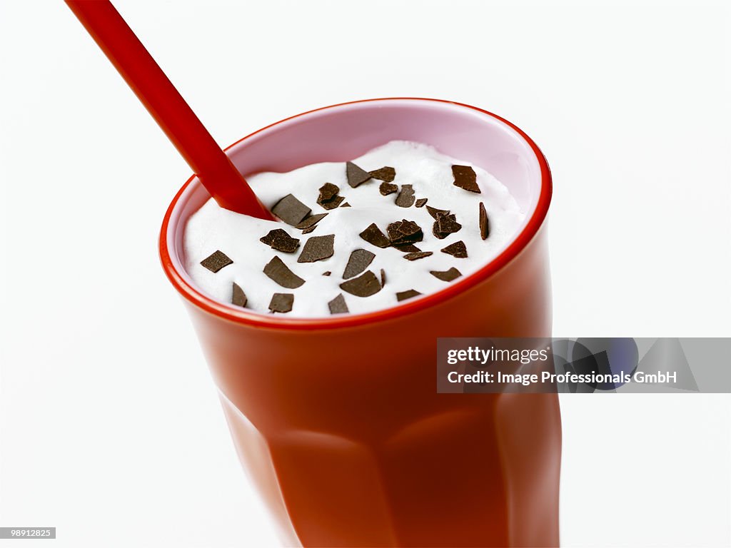 Milkshake with flakes of chocolate in red glass, close-up