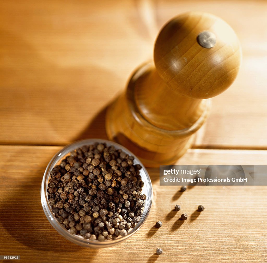 Peppercorns and pepper mill, overhead view, close-up