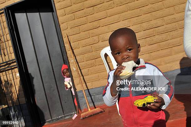 Child eats his breakfast at the front door of his family home in the township of Alexandra in Johannesburg on May 7, 2010. All of the street names in...