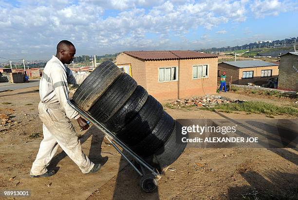 Roadside trye repair man takes his goods from his home to his open air work place in the township of Alexandra in Johannesburg on May 7, 2010. All of...