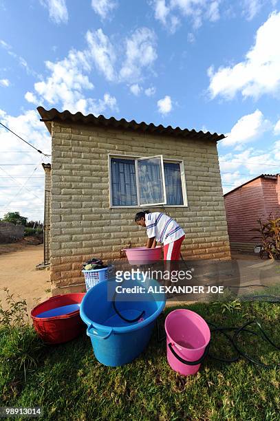 Woman does her washing in the front garden of her home in the township of Alexandra in Johannesburg on May 7, 2010. All of the street names in the...