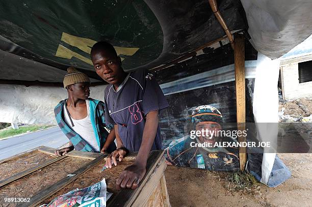 Young men take cover under a tent near a rugby poster in the township of Alexandra in Johannesburg on May 7, 2010. All of the street names in the...