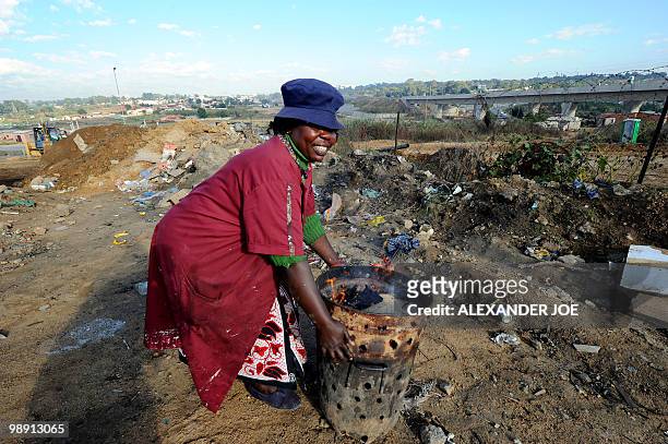 Vendor gets a fire ready to cook food at her roadside food stand in the township of Alexandra in Johannesburg on May 7, 2010. All of the street names...