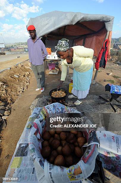 Vendor cooks doughnuts at her roadside food stall in the township of Alexandra in Johannesburg on May 7, 2010. All of the street names in the...