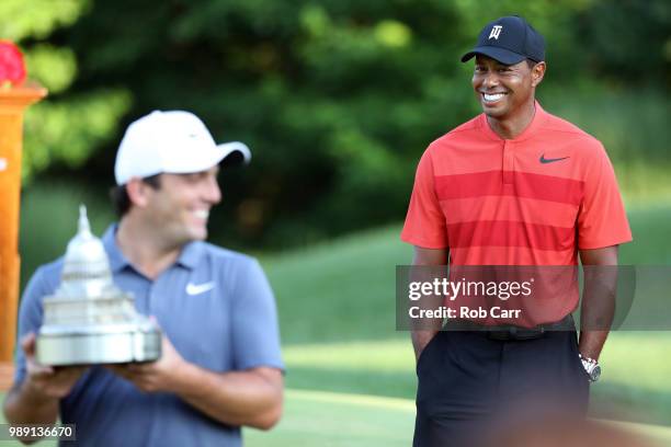 Francesco Molinari of Italy celebrates with the trophy after winning the Quicken Loans National as Tiger Woods looks on during the final round at TPC...