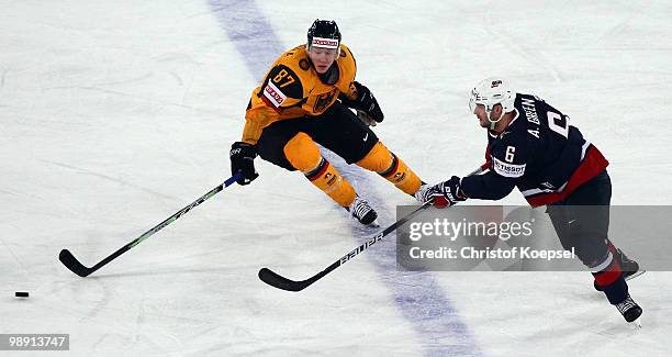 Philip Gogulla of Germany and Andy Greene of the United States fight for the puck during the IIHF World Championship group D match between USA and...