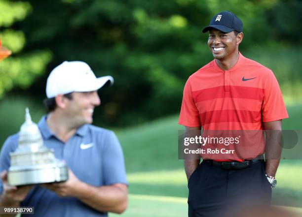 Francesco Molinari of Italy celebrates with the trophy after winning the Quicken Loans National as Tiger Woods looks on during the final round at TPC...