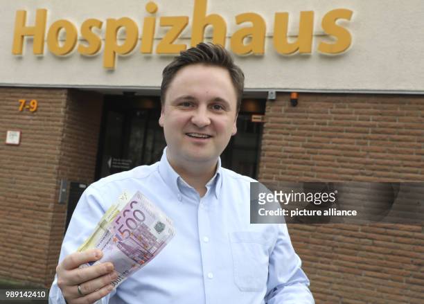Lucas Weiß, managing director of the hospice Wolfsburg stands in front of the hospice building holding an anonymous donation, in Wolfsburg, Germany,...