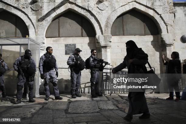 Palestinian woman passes by as Israeli policemen stand guard after Friday prayers in Jerusalem's Old City, 15 December 2017. Photo: Corinna Kern/dpa