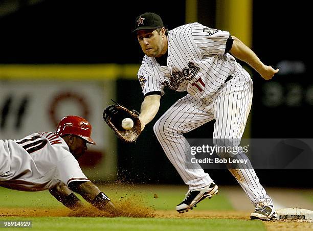 Justin Upton of the Arizona Diamondbacks dives back into first base as first baseman Lance Berkman of the Houston Astros receives the throw from...