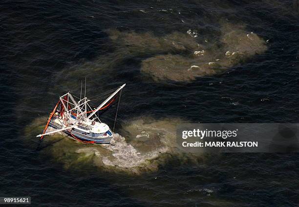 Fishing boat stirs up mud as it drags a boom through an oil slick that has passsed inside of the protective barrier formed by the Chandeleur Islands,...
