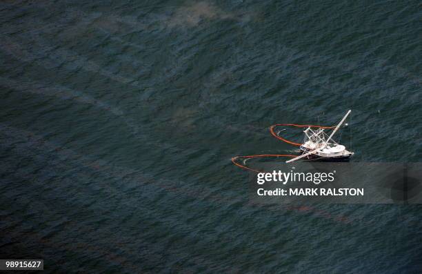 Fishing boat drags a boom through an oil slick that has passsed inside of the protective barrier formed by the Chandeleur Islands, as cleanup...