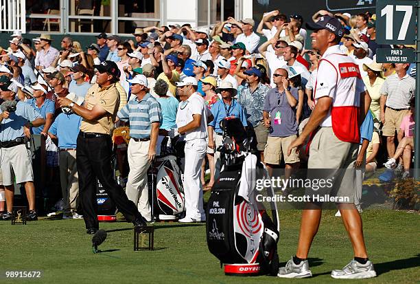 Phil Mickelson hits his tee shot on the 17th hole while his caddie Jim Mackay, Ernie Els of South Africa and caddie Dan Quinn look on during the...