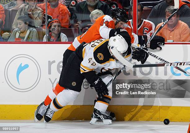 Kimmo Timonen of the Philadelphia Flyers battles for the loose puck along the boards with Trent Whitfield of the Boston Bruins in Game Four of the...