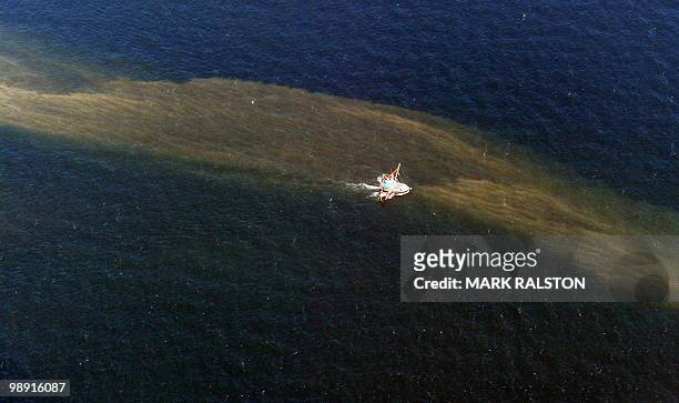 Fishing boat drags a boom through an oil slick that has passsed inside of the protective barrier formed by the Chandeleur Islands, as cleanup...