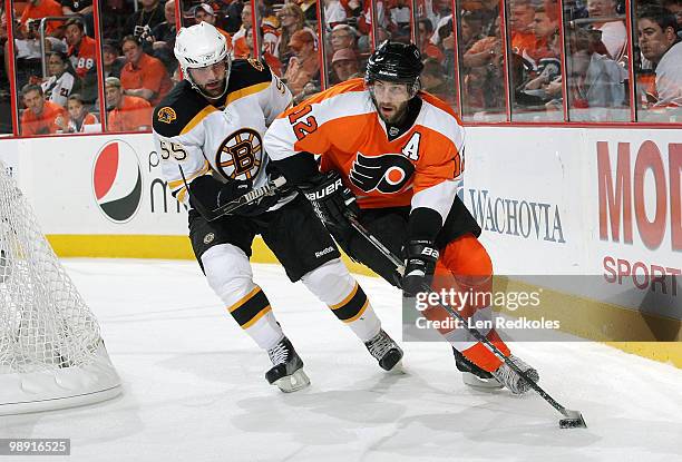 Simon Gagne of the Philadelphia Flyers skates with the puck behind the net while being pursued by Johnny Boychuk of the Boston Bruins in Game Four of...