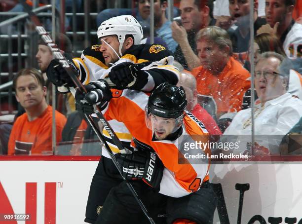 Danny Briere of the Philadelphia Flyers takes a hit along the boards from Steve Begin of the Boston Bruins in Game Four of the Eastern Conference...