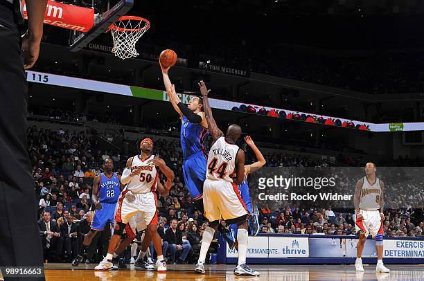 Nick Collison of the Oklahoma City Thunder shoots a layup against Corey Maggette and Anthony Tolliver of the Golden State Warriors during the game at...