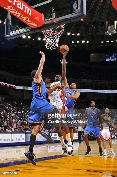 Ronny Turiaf of the Golden State Warriors shoots a layup against Thabo Sefolosha and Russell Westbrook of the Oklahoma City Thunder during the game...